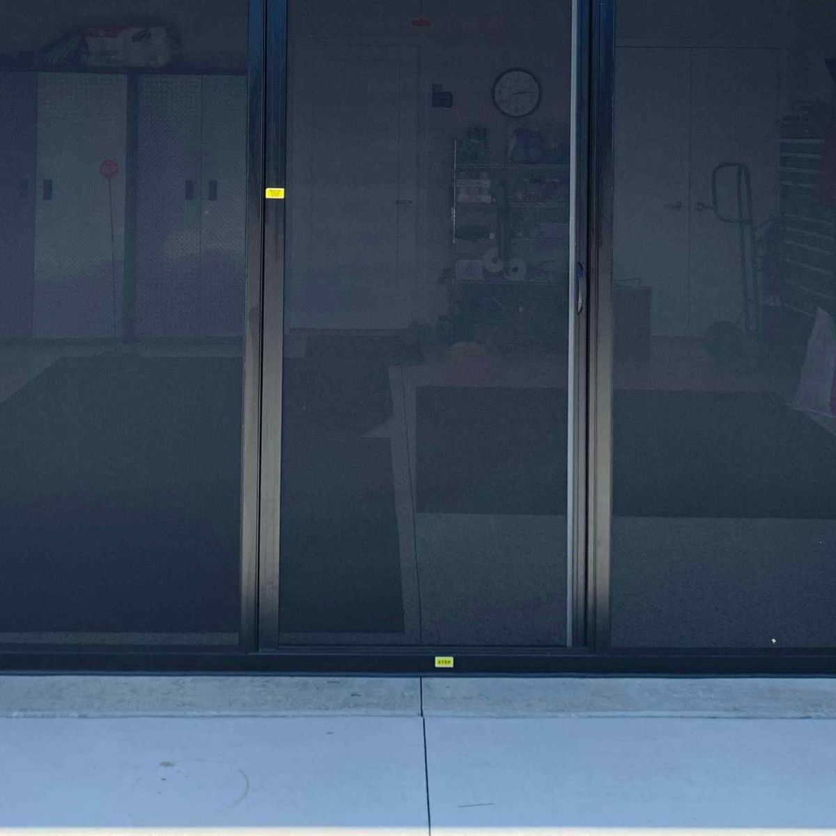 A retractable garage screen lowered across an open double garage doorway